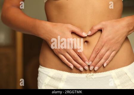 Den mittleren Abschnitt der jungen Frau mit Herz hand Geste Stockfoto
