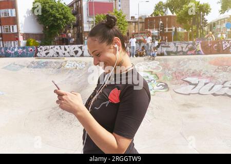 Junge Frau hört Musik Skate Park Stockfoto