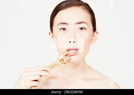 Junge Frau mit einem Schraubenschlüssel auf den Lippen Stockfoto