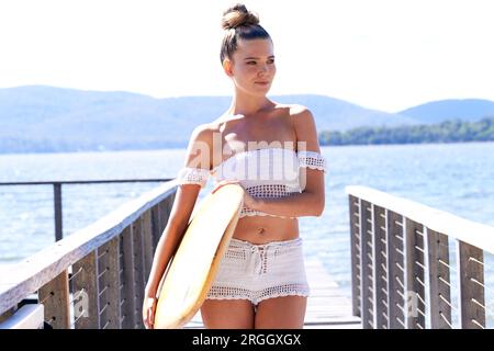 Junge Frau mit Surfbrett auf Pier posing Stockfoto