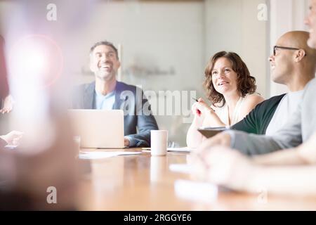 Reife Geschäftsfrau lächelnd mit Kollegen in Sitzung Stockfoto