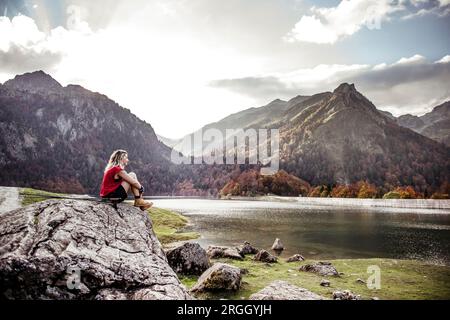 Junge Frau Wanderer ruht auf Rock am See Stockfoto