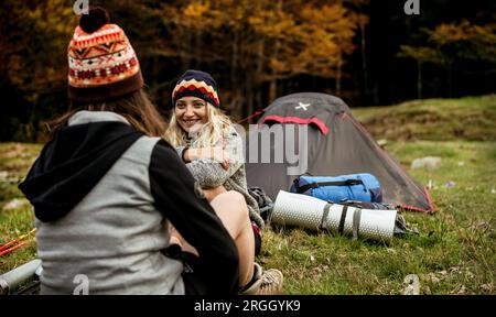 Junge Frau im Gespräch mit Freund beim Camping Stockfoto