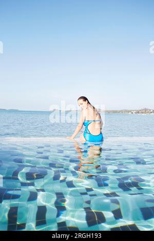 Junge Frau sitzt am Pool in Ko Samui, Thailand Stockfoto