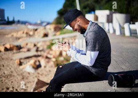 Junger Mann mit Smart Phone von Beach Stockfoto