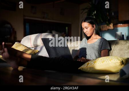 Junge Frau am Laptop von zu Hause aus arbeiten Stockfoto