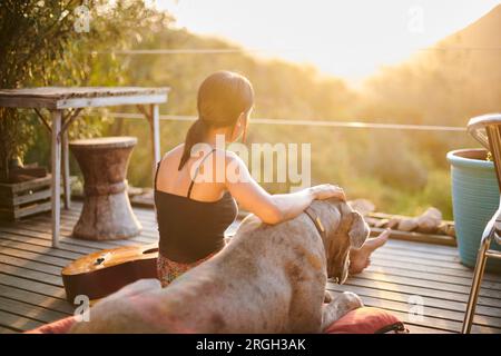 Junge Frau mit Hund Sonnenuntergang beobachten Stockfoto