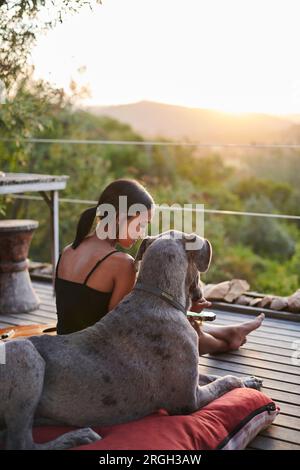Junge Frau mit Hund Sonnenuntergang beobachten Stockfoto