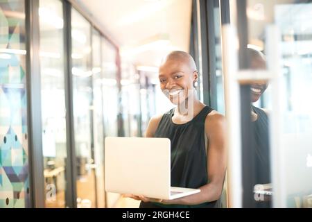 Junge Geschäftsfrau, die lächelt, während sie das Notebook in der Hand hält Stockfoto