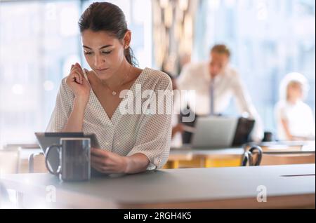 Geschäftsfrau, die ein digitales Tablet mit einer Kaffeetasse verwendet Stockfoto