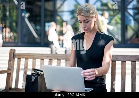 Geschäftsfrau mit Laptop auf Bank Stockfoto