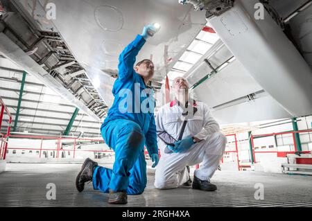 Männer mit Fackel unter dem Flugzeug knien Stockfoto