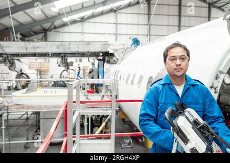 Mann, der ein Elektrowerkzeug im Flugzeug im Hangar hält Stockfoto