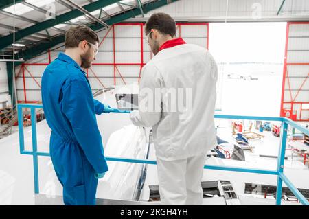 Männer, die ein digitales Tablet im Flugzeughangar benutzen Stockfoto