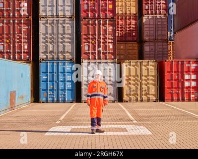 Hafenarbeiter durch Stapel von Frachtcontainern Stockfoto