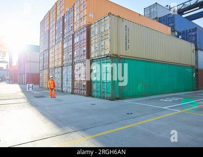 Hafenarbeiter durch Stapel von Cargo Container im Hafen von Felixstowe, England Stockfoto