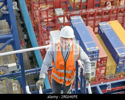 Dock worker klettern Schritte der Kran Stockfoto