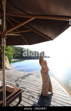 Junge Frau mit Handtuch am Pool Stockfoto