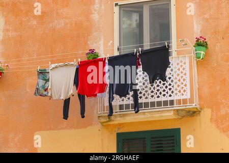 Wäschetag in Amalfi, Italien, gewaschene Kleidung trocken in einer mediterranen Brise auf einer Wäscheleine zwischen zwei Balkonen, auf einer bunten Fassade. Stockfoto