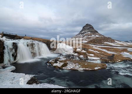 Am Fuße des Wasserfalls Kirkjufellsfoss, der halb vereist ist und nicht so viel Wasser durchfließt wie im Sommer. Stockfoto