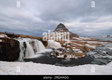 Am Fuße des Wasserfalls Kirkjufellsfoss, der halb vereist ist und nicht so viel Wasser durchfließt wie im Sommer. Stockfoto