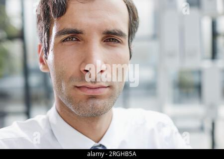 Porträtaufnahme eines seriösen, konzentrierten Geschäftsmannes, der ein weißes Hemd trägt und in die Kamera schaut. Stockfoto