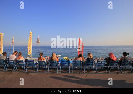 Die Menschen sitzen auf blauen Stühlen an der französischen Riviera Promenade in Nizza Stockfoto