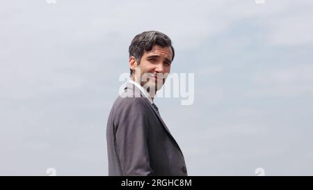Junger gutaussehender und freundlicher Mann lächelt, mit fröhlichem und selbstbewusstem positiven Ausdruck auf Studioaufnahmen im weißen Hintergrund. Stockfoto