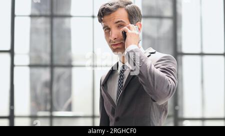 Junger Geschäftsmann, der im Büroflur ein Handy benutzt Stockfoto