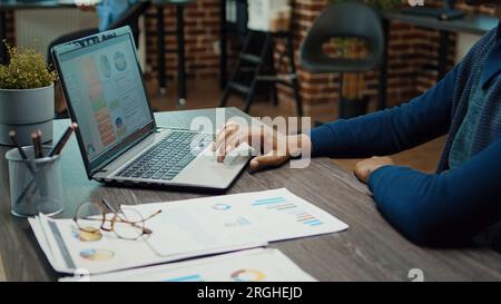 Junger Geschäftsmann, der mit einem Notebook arbeitet und Unternehmensanalysen prüft, versucht, den Gewinn mit jährlichen Statistiken zu steigern. Mitarbeiter im Startup-Office plant Unternehmensentwicklung, Datenberichte. Stockfoto