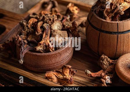 Getrocknete Pfifferlingpilze (Cantharēllus cibārius) auf einer Holzplatte, auf einem rauen gewebten Hintergrund, Leinenbildung Stockfoto