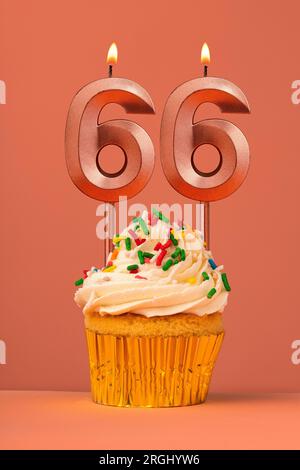 Kerze Nummer 66 - Kuchen zum Geburtstag im Hintergrund der Korallenverschmelzung Stockfoto