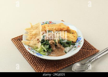 Nasi Pecel Madiun, traditionelles indonesisches Menü mit scharfer Erdnusssoße, Tempeh, gekochtem Gemüse, Rempeyek. Beliebt zum Frühstück, Abendessen oder Mittagessen Stockfoto