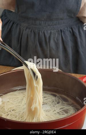 Weibliche Hand-Cooking-Somen oder Somyeon, asiatische weiße Nudeln, beliebt in Korea und Japanisch. Schritt für Schritt Nudelsuppe machen Stockfoto