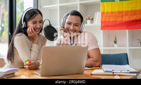 Ein attraktiver und glücklicher asiatischer Homosexueller spricht gern, liest Kommentare online und nimmt mit seiner Studiokollegin Audio-Podcasts auf. Stockfoto