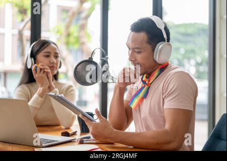 Ein professioneller und fokussierter asiatischer Homosexueller, der Kopfhörer trägt, spricht und interviewt seinen Gast im Studio. Stockfoto