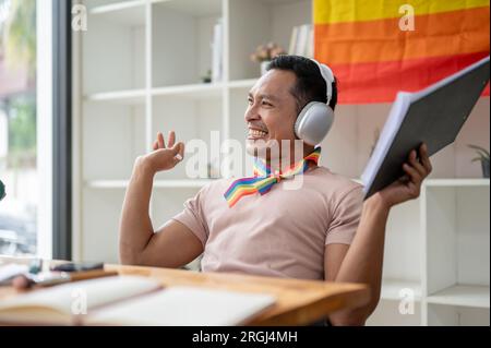 Ein attraktiver und fröhlicher asiatischer Homosexueller spricht gern, während er mit seinem Gast in seinem Sendestudio Audio-Podcasts aufnimmt. Stockfoto