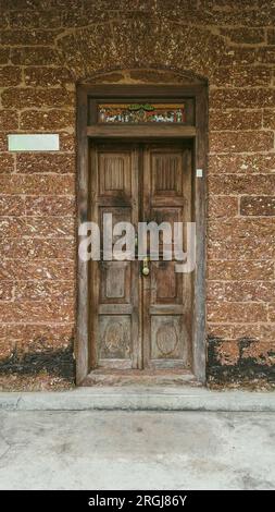 Ein Eingang zu einem altmodischen Haus mit einer alten Holztür und Wänden aus roten Ziegelsteinen Stockfoto