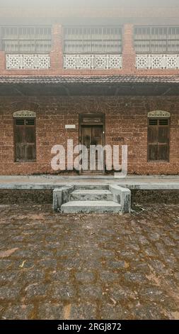 Vorderansicht eines alten Palastes aus roten Ziegelsteinen mit alten Holztüren und Fenstern Stockfoto