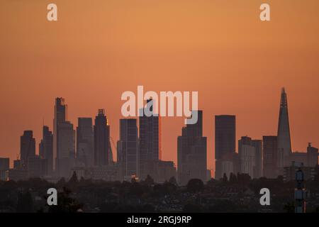 Wimbledon, London, Großbritannien. 10. Aug. 2023. Die Temperaturen in London sind heute bei angenehmen 25 Grad am höchsten. Ein orangefarbener Himmel bei Sonnenaufgang mit Wolkenkratzern im Zentrum von London, die die ersten Sonnenstrahlen einfangen. Kredit: Malcolm Park/Alamy Live News Stockfoto