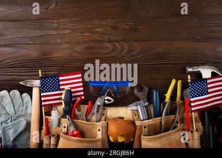 Labour Day Bannermodell von Werkzeuggürtel und US-Flagge auf Holzhintergrund Stockfoto