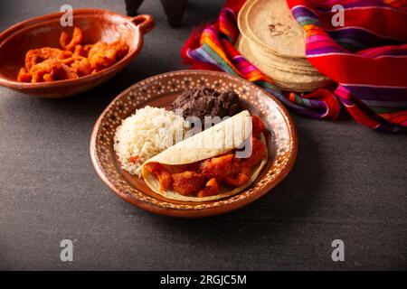 Chicharron en Salsa roja. Schweineschalen in roter Sauce, dazu Reis und gekühlte Bohnen. Traditionelles hausgemachtes Gericht, sehr beliebt in Mexiko, dies Stockfoto