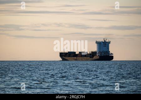 Containerschiff geht vor dem Hintergrund des blauen Himmels auf See, Frachttransport, Logistik, Import und Export von Gütern. Stockfoto