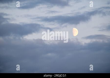 Hellblauer Himmelshintergrund mit Mond und Wolken. mondlicht in weißen Wolken. Stockfoto