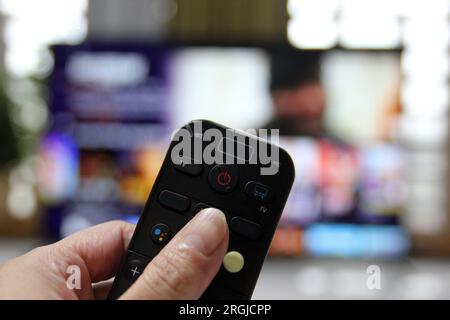 Kabelschneider, die fernsehen und die Fernbedienung verwenden Stockfoto