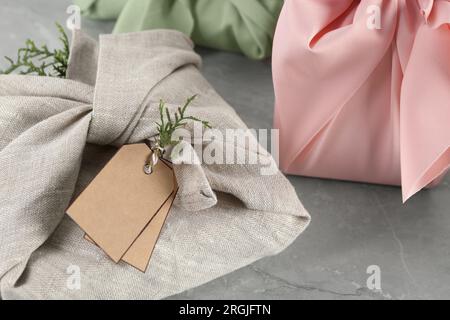 Furoshiki-Technik. Geschenke in Stoff auf grauem Tisch, Nahaufnahme Stockfoto