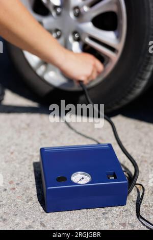 Nahaufnahme eines Mannes, der den Luftdruck prüft und Luft in den Reifen des Fahrzeugs einfüllt Stockfoto