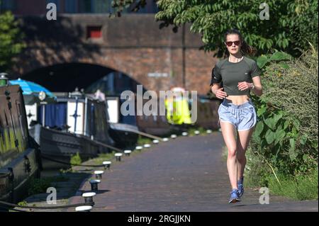 Brindley Place Birmingham, 10. August 2023: In Birmingham haben sich die Menschen in der heißen Morgensonne sportlich betätigt, bevor die Temperaturen in Midlands-Stadt voraussichtlich 26 Grad erreichen werden. Ein Hund namens Dash durfte sogar unter einem Sonnenschirm auf seinem Kanalboot sitzen und eine Kaugummi essen. Kredit: Stop Press Media/Alamy Live News Stockfoto