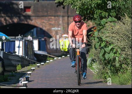 Brindley Place Birmingham, 10. August 2023: In Birmingham haben sich die Menschen in der heißen Morgensonne sportlich betätigt, bevor die Temperaturen in Midlands-Stadt voraussichtlich 26 Grad erreichen werden. Ein Hund namens Dash durfte sogar unter einem Sonnenschirm auf seinem Kanalboot sitzen und eine Kaugummi essen. Kredit: Stop Press Media/Alamy Live News Stockfoto