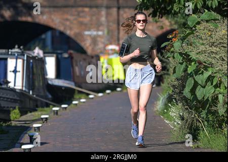 Brindley Place Birmingham, 10. August 2023: In Birmingham haben sich die Menschen in der heißen Morgensonne sportlich betätigt, bevor die Temperaturen in Midlands-Stadt voraussichtlich 26 Grad erreichen werden. Ein Hund namens Dash durfte sogar unter einem Sonnenschirm auf seinem Kanalboot sitzen und eine Kaugummi essen. Kredit: Stop Press Media/Alamy Live News Stockfoto